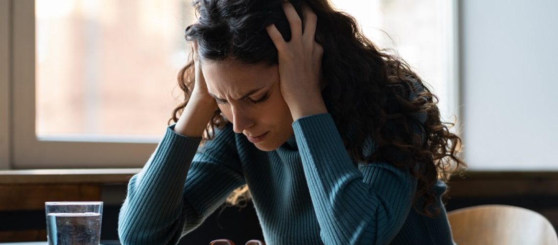 Unhappy female overworked and stressed sit at desk with closed laptop suffer from headache, depression feeling exhausted frustrated with bad news, failure at work. Tired sick woman worker in office