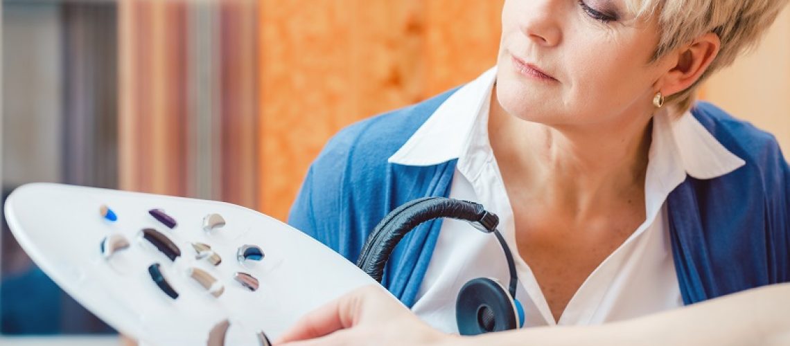 Senior woman with impairment choosing hearing aid in shop