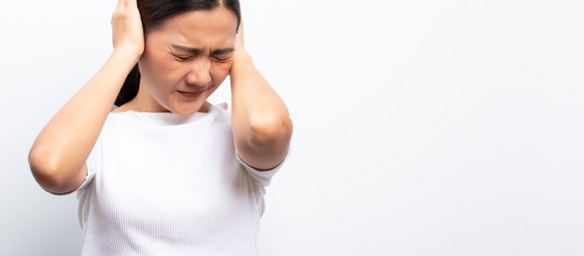 Sad woman covering her ears standing isolated over white background